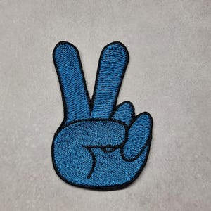 May include: A blue embroidered peace sign patch with black stitching.