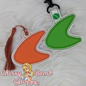 May include: Two retro-style keychains. One is orange, the other is green, both with a white glittery border and black clip. The orange keychain has a brown tassel. The text "Chevy Bomb Shoppe" is at the bottom.