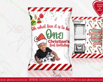 May include: A white chip bag with red and white stripes around the edges. The bag has a Christmas theme with candy canes, ornaments, and a gingerbread man. The text on the bag reads "Oh what fun it is to be One! Christian's first birthday". A photo of a baby boy wearing a Santa hat is in the center of the bag.