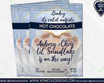 Könnte beinhalten: Ein blaues und weißes Winter-Heißgetränke-Paket mit dem Text "Baby it's cold outside HOT CHOCOLATE" und "Aubrey & Chris' lil Snowflake is on the way!" Das Paket enthält Anweisungen, um Milch oder heißes Wasser zum Kakao-Mix hinzuzufügen. Das Nettogewicht beträgt 0,73 oz.
