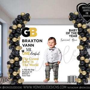 Könnte beinhalten: Ein Schwarz-Gold-Ballonbogen mit einem Magazincover, auf dem ein Babyjunge in einem weißen Hemd und einer karierten Hose zu sehen ist. Das Magazincover lautet "Baby des Jahres" und "Braxton Vann Mr. One-derful".