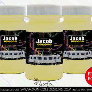 May include: Three clear plastic bottles with yellow liquid inside. Each bottle has a black and white label with a subway map design and the text "Jacob Turns 7". The bottles are on a white marble surface. The text "Fits 4oz Bottles" is in red on a white circle.