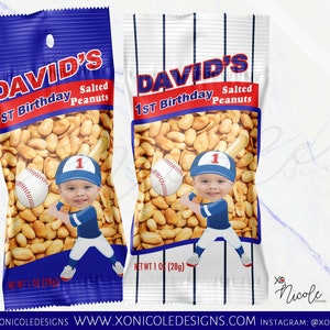 May include: Two blue and white personalized snack bags with a baseball theme. The bags are filled with peanuts and feature a photo of a child wearing a baseball uniform. The bags say "David's 1st Birthday Salted Peanuts" on the front.