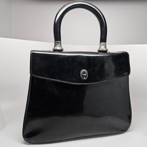 Cartera vintage Anya Hindmarch de charol con asa superior, interior de gamuza y detalles ornamentales