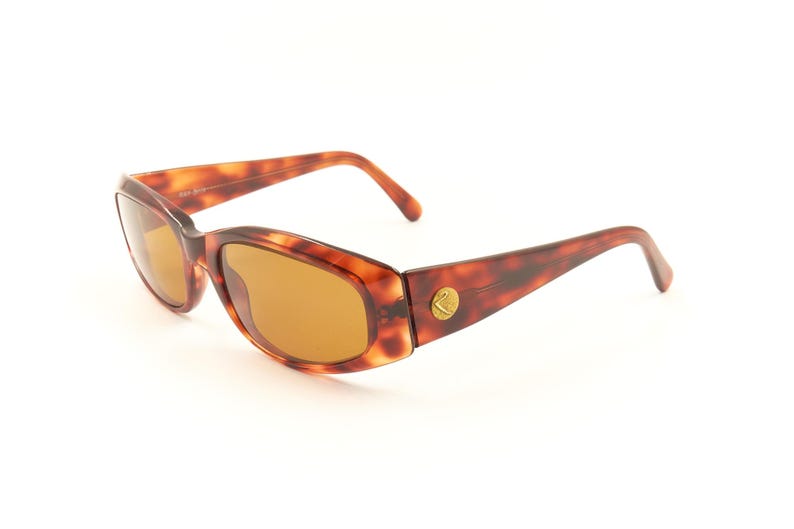 May include: Tortoise shell sunglasses with brown lenses. The sunglasses have a gold logo on the side.