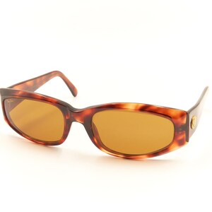 May include: Tortoise shell sunglasses with brown lenses. The sunglasses have a classic, retro style.