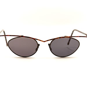 May include: A pair of tortoiseshell and silver oval-shaped sunglasses with dark gray lenses.