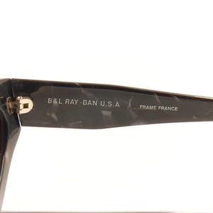 Pode incluir: &Oacute;culos de sol preto e cinza com padr&atilde;o de m&aacute;rmore com o texto "B&L RAY-BAN U.S.A. FRAME FRANCE" na lateral.