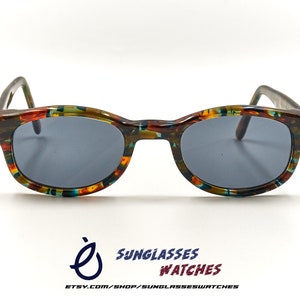 May include: Vintage sunglasses with a colourful, abstract pattern on the frames. The lenses are dark grey.