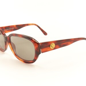 May include: Tortoise shell sunglasses with brown lenses and a gold logo on the side.