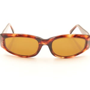 May include: Tortoise shell sunglasses with brown lenses. The sunglasses have a rectangular shape with rounded edges.