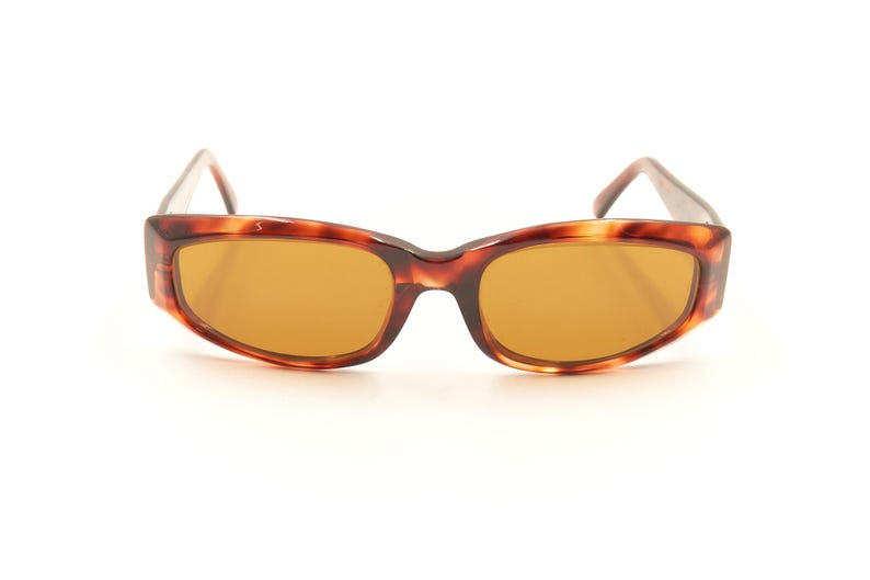 May include: Tortoise shell sunglasses with brown lenses. The sunglasses have a rectangular shape with rounded edges.