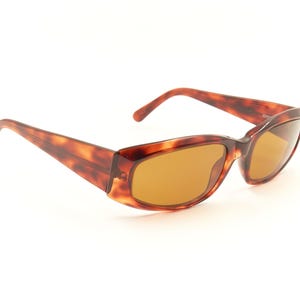 May include: Tortoise shell sunglasses with brown lenses. The sunglasses have a rectangular shape and a thin frame.