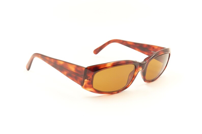 May include: Tortoise shell sunglasses with brown lenses. The sunglasses have a rectangular shape and a thin frame.