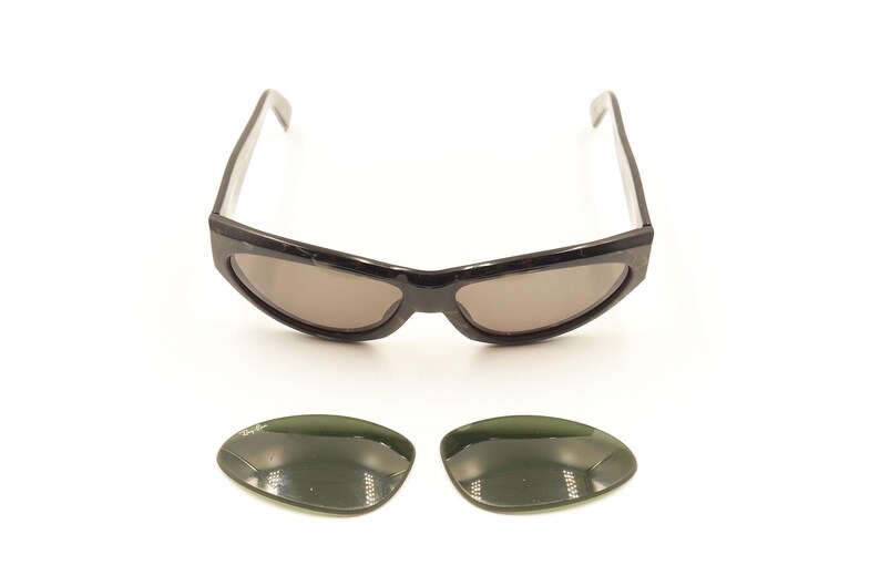 Pode incluir: &Oacute;culos de sol pretos com arma&ccedil;&atilde;o curva e lentes cinza escuras. Inclui duas lentes de reserva, tamb&eacute;m cinza escuras.