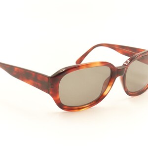 May include: Tortoise shell sunglasses with oval-shaped lenses and a brown frame.