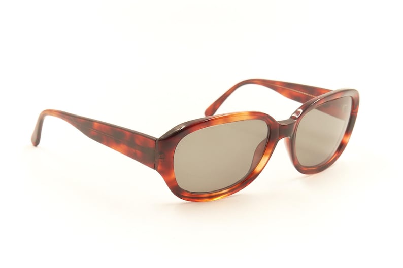 May include: Tortoise shell sunglasses with oval-shaped lenses and a brown frame.