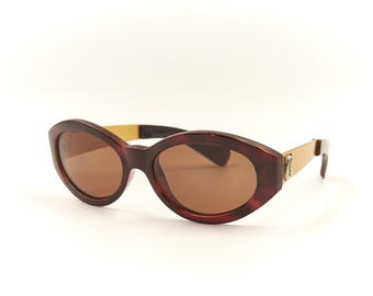 Puede incluir: Gafas de sol de carey marrón con detalles dorados y lentes marrones.