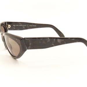 Pode incluir: &Oacute;culos de sol de tartaruga preta com lentes marrons escuras. Os &oacute;culos t&ecirc;m o logotipo Ray-Ban na lateral.