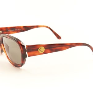 May include: Tortoise shell sunglasses with brown lenses and a gold logo on the side.