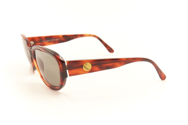 May include: Tortoise shell sunglasses with brown lenses and a gold logo on the side.