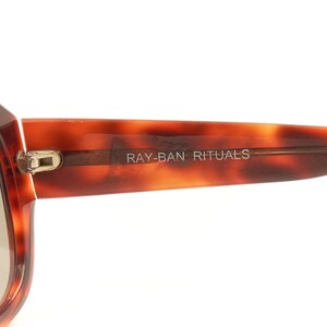 May include: Close-up of a pair of tortoiseshell sunglasses with the text "RAY-BAN RITUALS" on the frame.