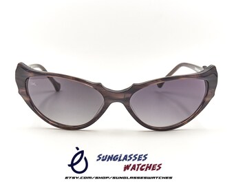 May include: Brown cat-eye sunglasses with a tortoiseshell pattern. The sunglasses have a dark gray lens.