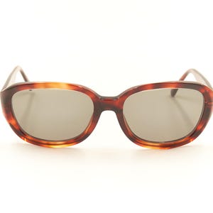 May include: Tortoise shell sunglasses with brown lenses. The sunglasses have a rounded, oval shape.