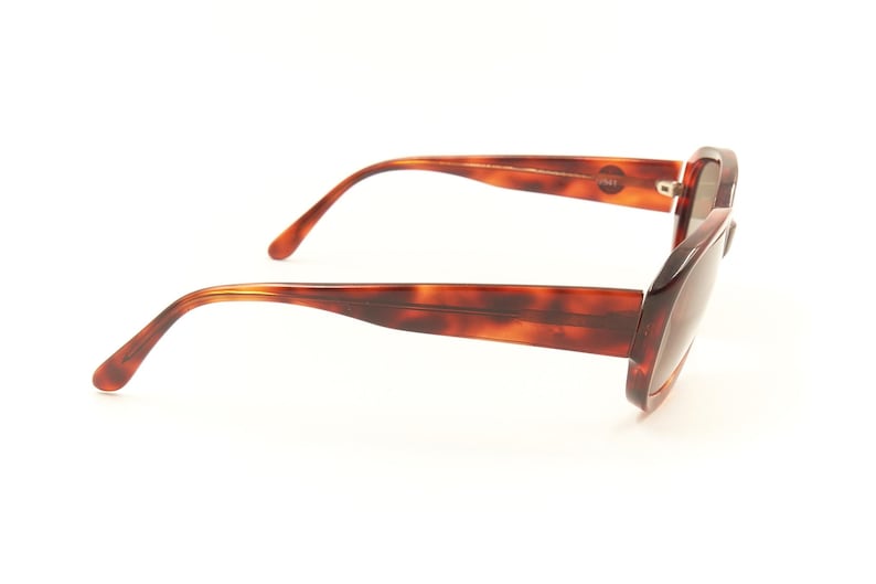 May include: Tortoise shell sunglasses with brown lenses. The sunglasses have a rectangular frame and are shown from the side.