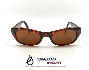 May include: Tortoise shell sunglasses with brown lenses. The sunglasses have a cat-eye shape.