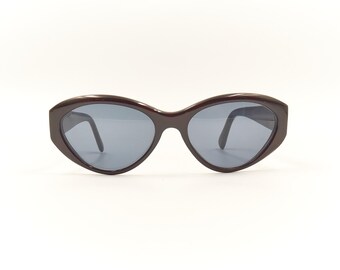 May include: A pair of dark brown cat-eye sunglasses with dark gray lenses.