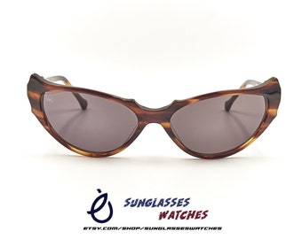 May include: Brown tortoiseshell cat-eye sunglasses with dark gray lenses. The sunglasses have a thin metal bridge and arms.
