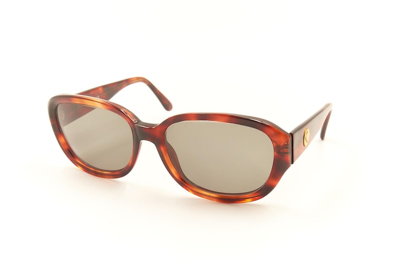 May include: Tortoise shell sunglasses with brown lenses. The sunglasses have a classic oval shape.