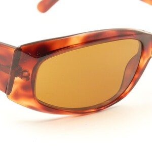 May include: Brown tortoise shell sunglasses with brown lenses. The sunglasses have a rectangular shape.
