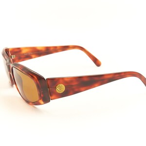 May include: Tortoise shell sunglasses with brown lenses. The sunglasses have a gold logo on the side.