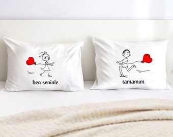 May include: Two white pillowcases with red hearts and stick figure drawings. The left pillowcase says "ben seninle" and the right pillowcase says "tamamım".