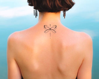Puede incluir: Primer plano de la espalda de una persona con un pequeño tatuaje de libélula en la nuca.