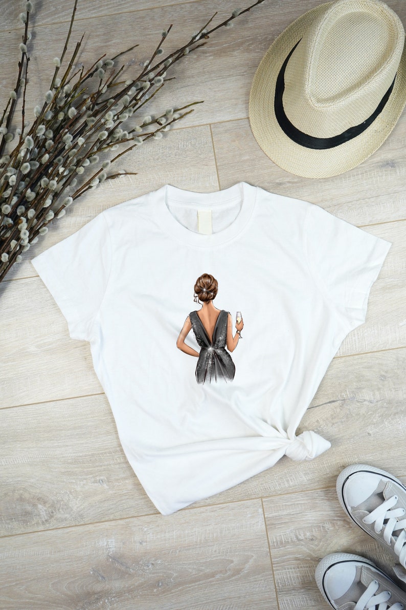 May include: White t-shirt with a graphic of a woman in a black dress holding a glass of champagne.