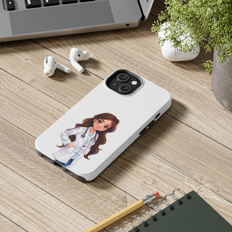 May include: A white phone case with a cartoon illustration of a female doctor wearing a white coat and stethoscope. The doctor has long brown hair and is smiling. The phone case has a camera lens cutout and a white background.