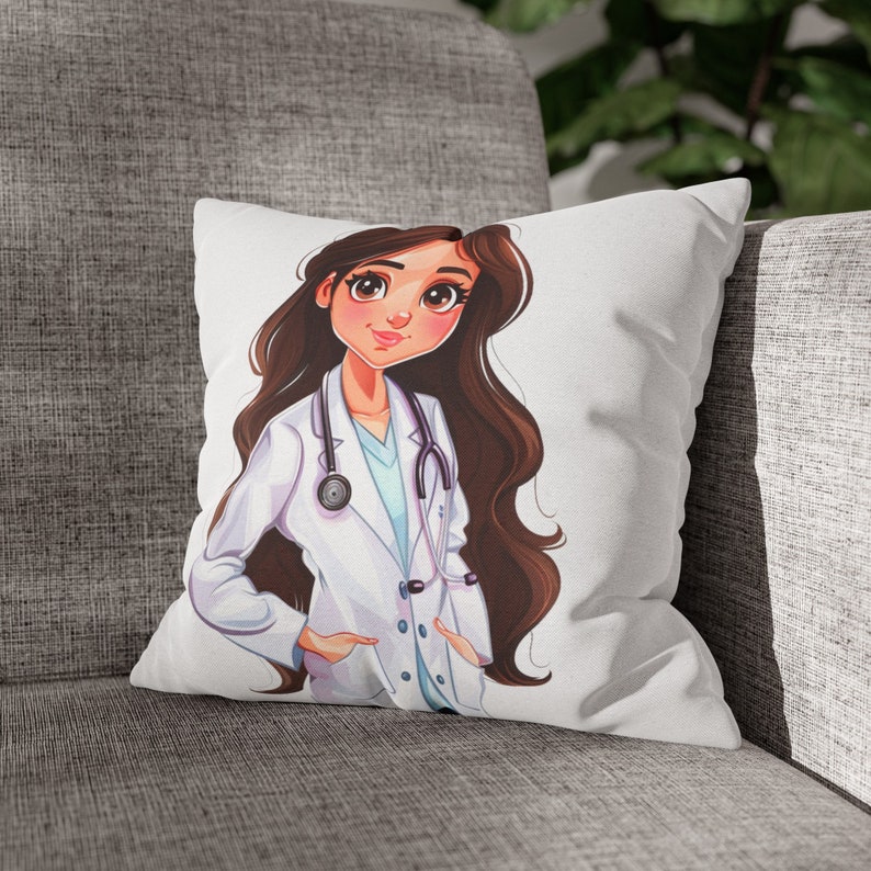 May include: A white throw pillow with a cartoon illustration of a female doctor with long brown hair. The doctor is wearing a white lab coat with a stethoscope around her neck. The doctor is smiling and has her hands in her pockets.