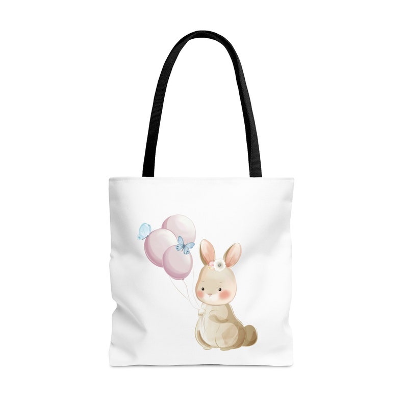 May include: A white tote bag with black handles features a watercolor illustration of a brown bunny holding pink balloons with blue butterflies.