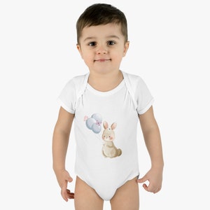 May include: A white baby onesie with a brown bunny holding blue balloons. The bunny has a pink bow on its head.
