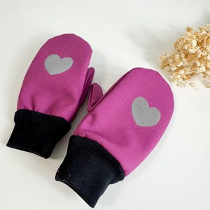 May include: Magenta mittens with a reflective grey heart on each. The cuffs are black. These winter gloves are designed for warmth and visibility.