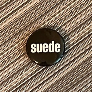 May include: A black button with the word "Suede" printed in white.