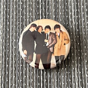 May include: A round button featuring a black and white photo of four men in suits and coats. The men are standing together and looking at the camera. The button is about 2 inches in diameter.