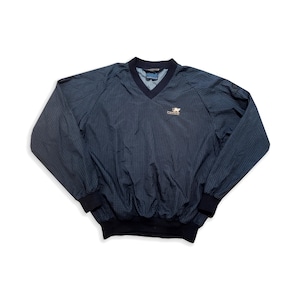 May include: A navy and black checked pullover jacket with a V-neck collar and long sleeves. The jacket features a small logo on the chest and elastic cuffs and hem. The jacket is made of a lightweight material.