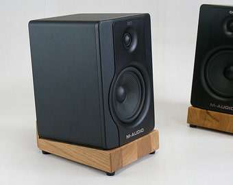 May include: Two black M-Audio studio monitors with wooden stands. The speakers have a black front panel with a silver M-Audio logo and a black speaker grille.