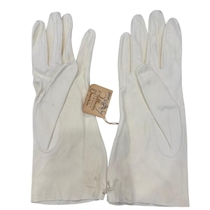 May include: A pair of white gloves with a light brown paper tag attached by a string. The tag features the text "Gloves by Pullman", "Washable", "Doeskin", and "Made in England" with a small graphic illustration of a glove.