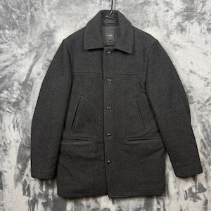 May include: A charcoal grey wool-blend coat featuring a structured collar, a front button placket with five visible buttons, long sleeves, and two slanted welt pockets on the chest with two additional horizontal pockets located at the waist.