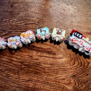 以下が含まれることがあります： 青、緑、黄、赤、白の機関車と車両を持つカラフルな玩具の列車セット。列車はセラミック製で、ペイントされたディテールがあります。